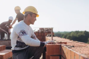 Worker laying bricks at an outdoor construction site, featured by Los Angeles Stucco Build & Repair.