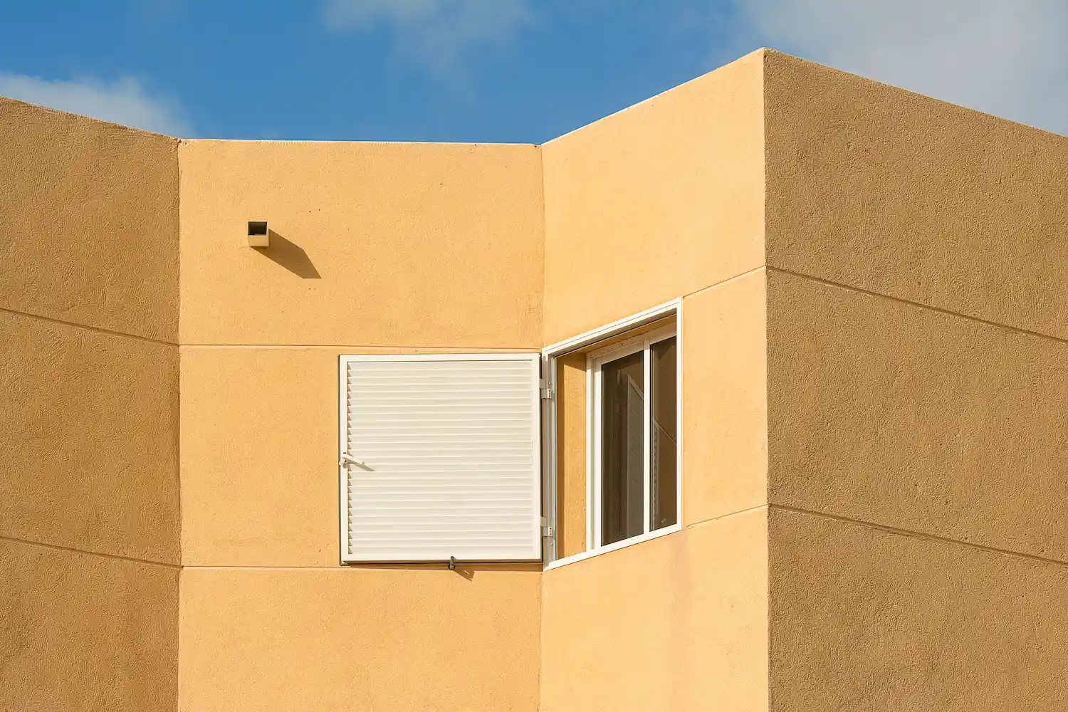 Golden stucco building exterior with white-framed windows, image for Los Angeles Stucco Build & Repair.
