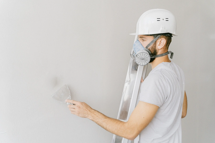 Worker wearing a respirator while finishing a wall, featured by Los Angeles Stucco Build & Repair.
