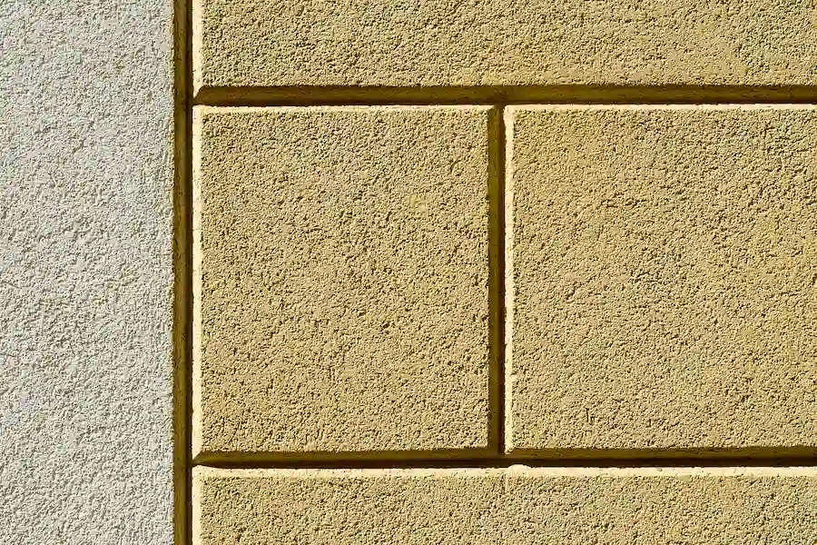 Yellow textured wall with recessed rectangular lines, image for Los Angeles Stucco Build & Repair.
