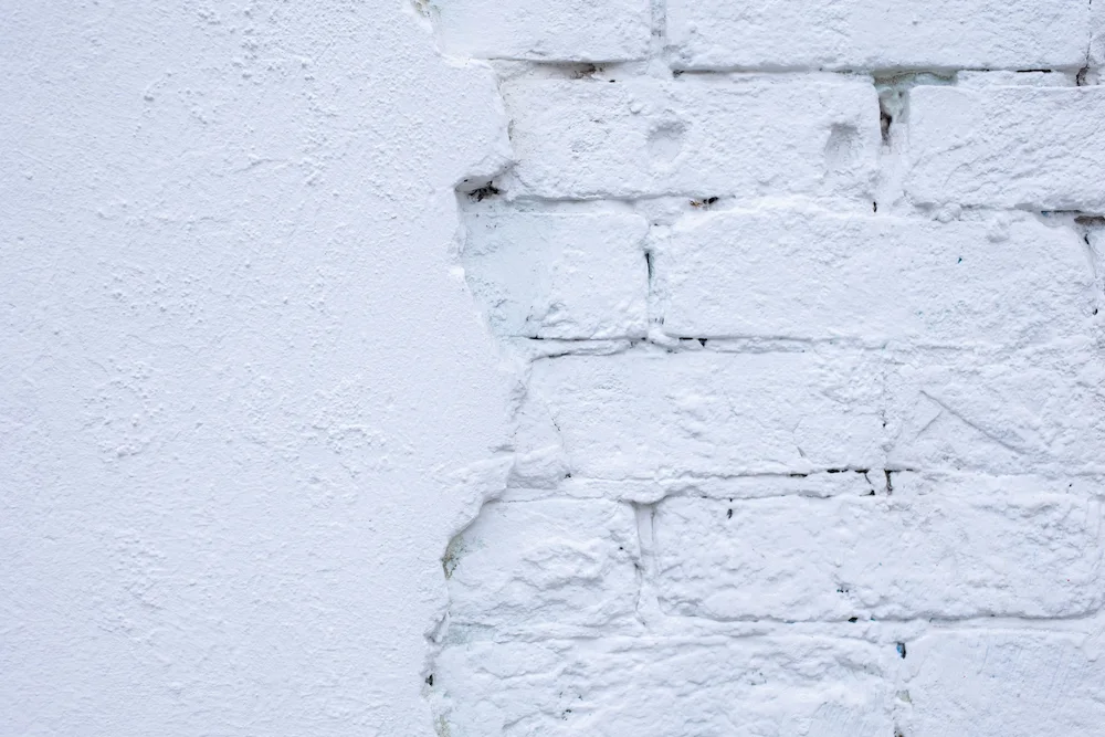 White wall with plaster beside visible brickwork, image for Los Angeles Stucco Build & Repair.